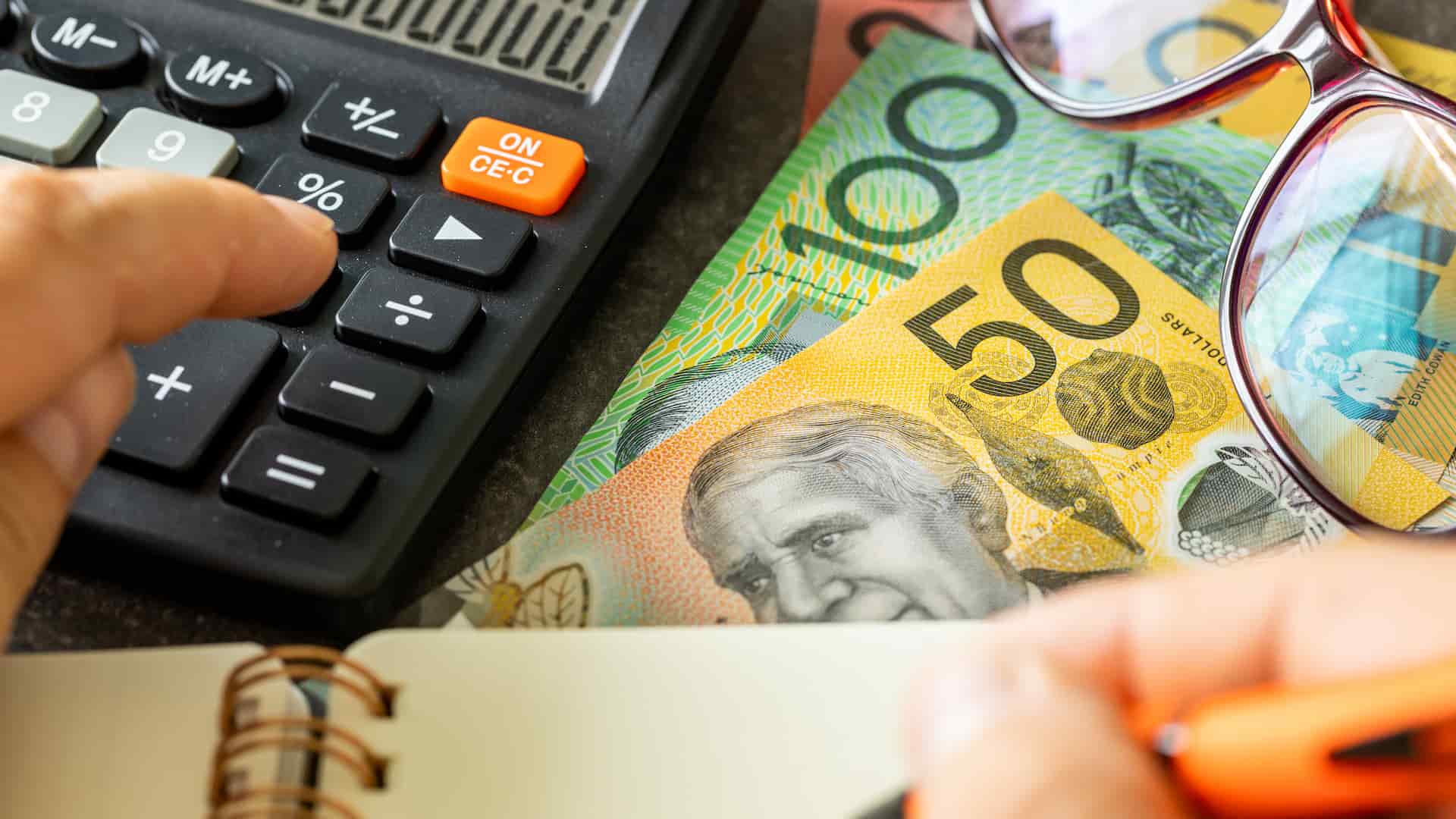 Calculator, notepad and money on table showing how to lodge a business tax return