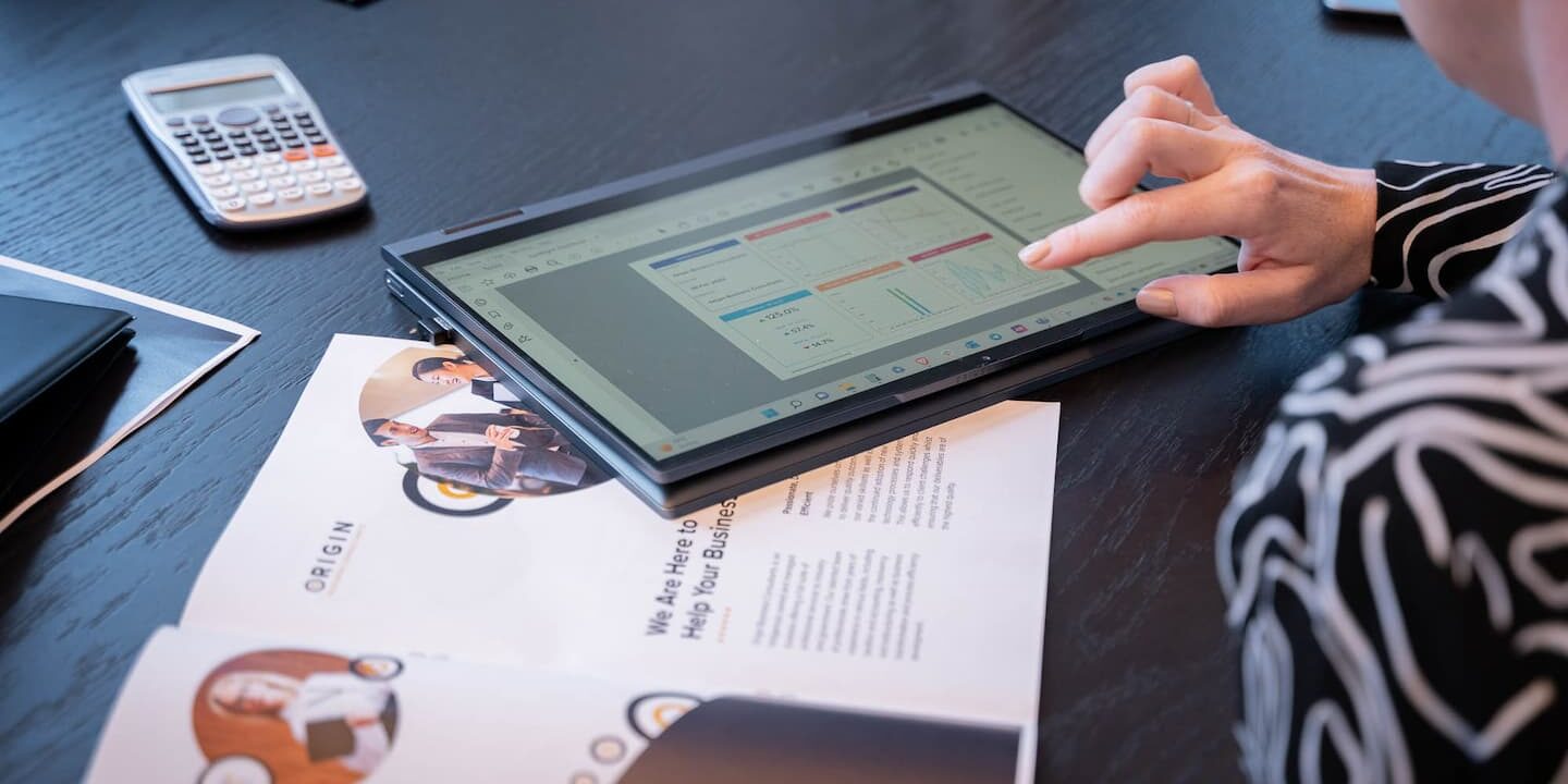 Tablet, calculator and sheet of paper on table with hand touching table explaining what is business tax planning and how to do it
