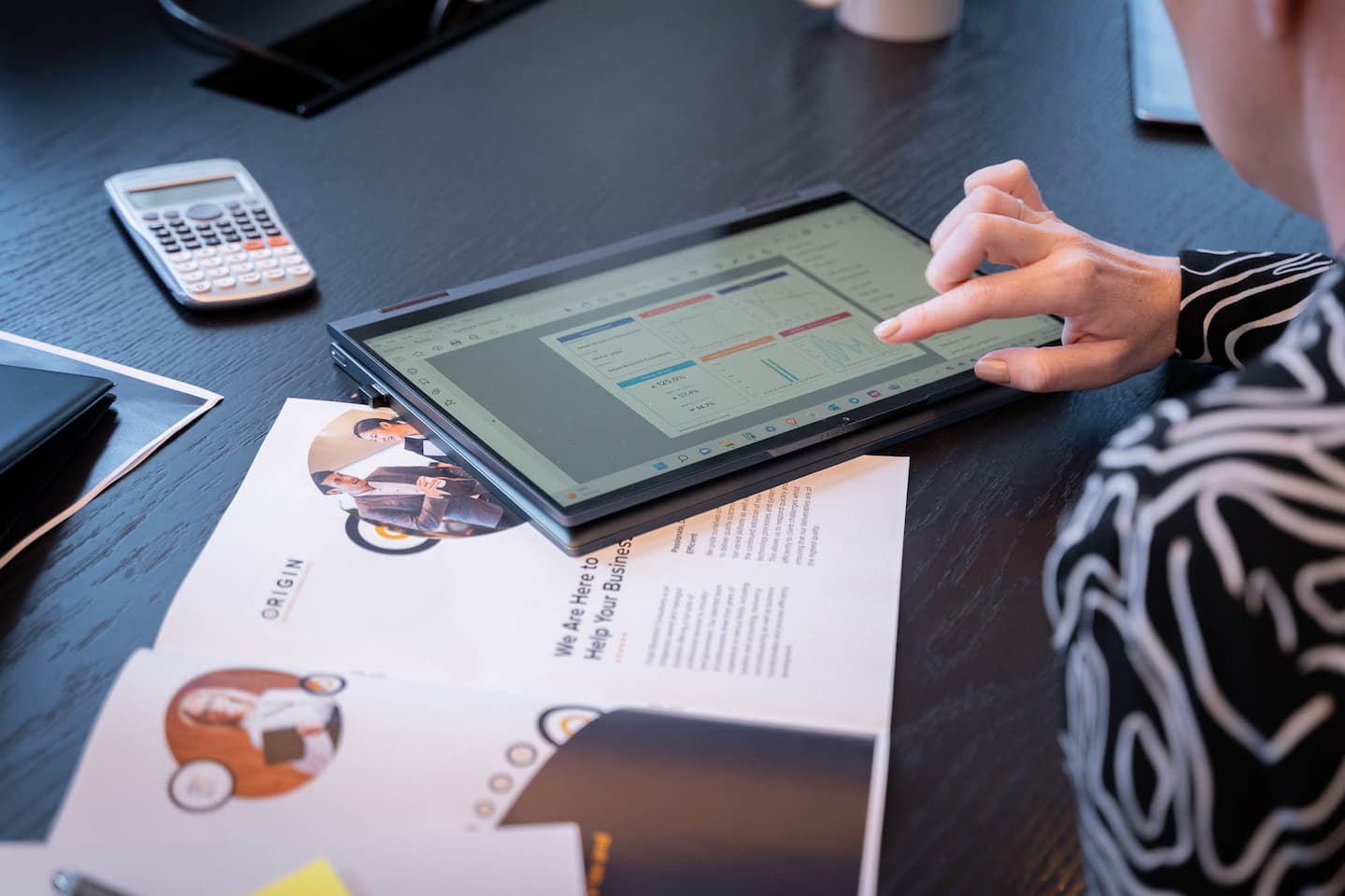Tablet, calculator and sheet of paper on table with hand touching table explaining what is business tax planning and how to do it
